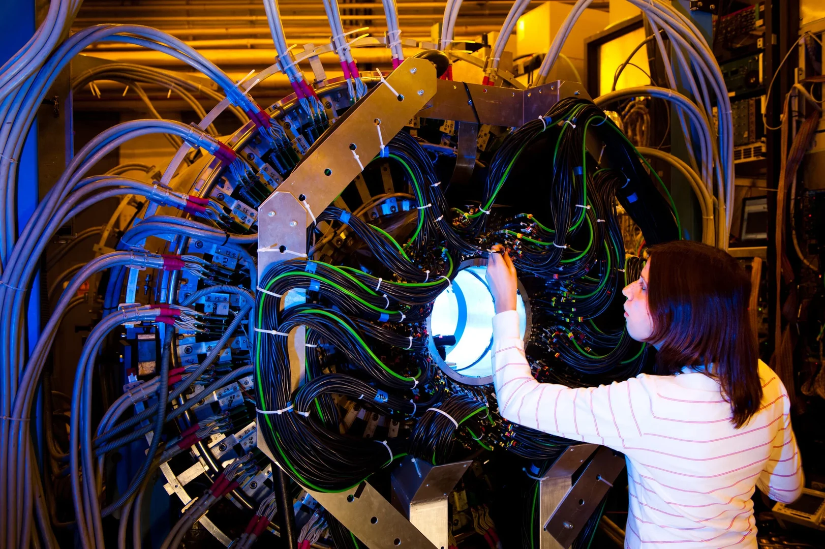 Eine Wissenschaftlerin und ein Wissenschaftler arbeiten hinter einer Glasfassade und mischen Chemikalien mit Großgeräten.