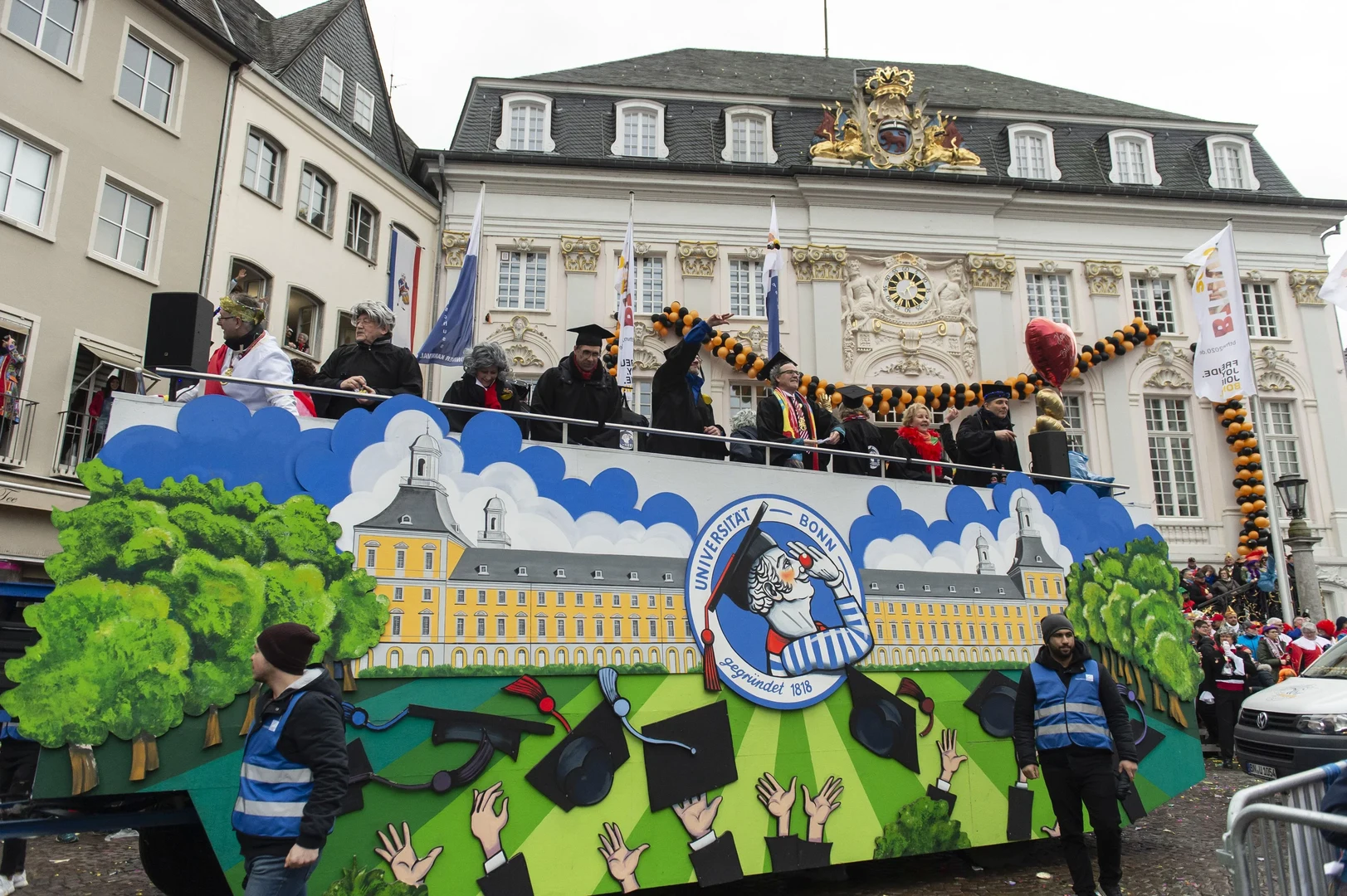 Eine Wissenschaftlerin und ein Wissenschaftler arbeiten hinter einer Glasfassade und mischen Chemikalien mit Großgeräten.