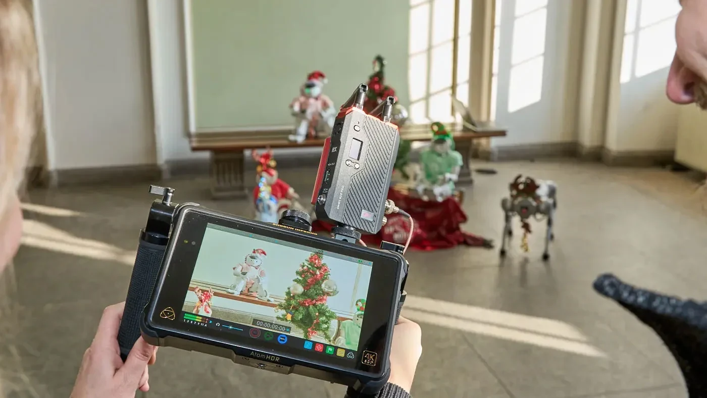 Eine Wissenschaftlerin und ein Wissenschaftler arbeiten hinter einer Glasfassade und mischen Chemikalien mit Großgeräten.