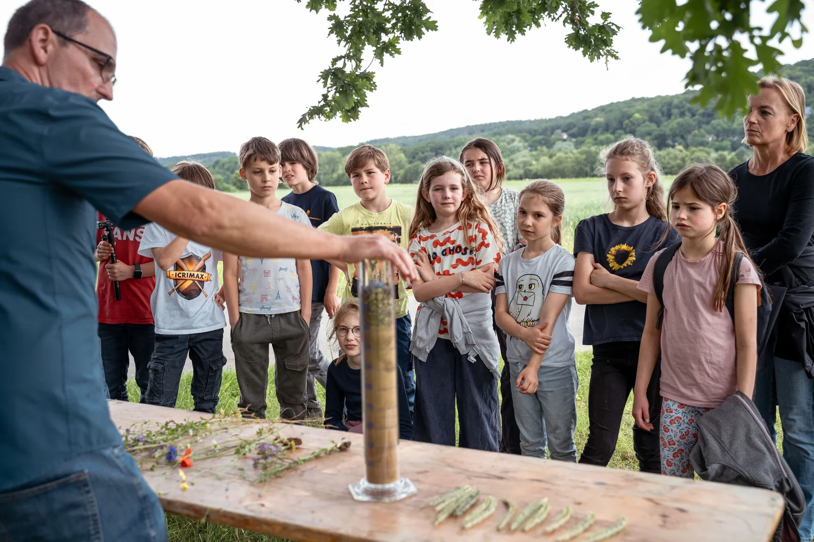 Eine Wissenschaftlerin und ein Wissenschaftler arbeiten hinter einer Glasfassade und mischen Chemikalien mit Großgeräten.
