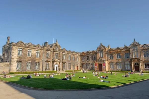 Eine Wissenschaftlerin und ein Wissenschaftler arbeiten hinter einer Glasfassade und mischen Chemikalien mit Großgeräten.