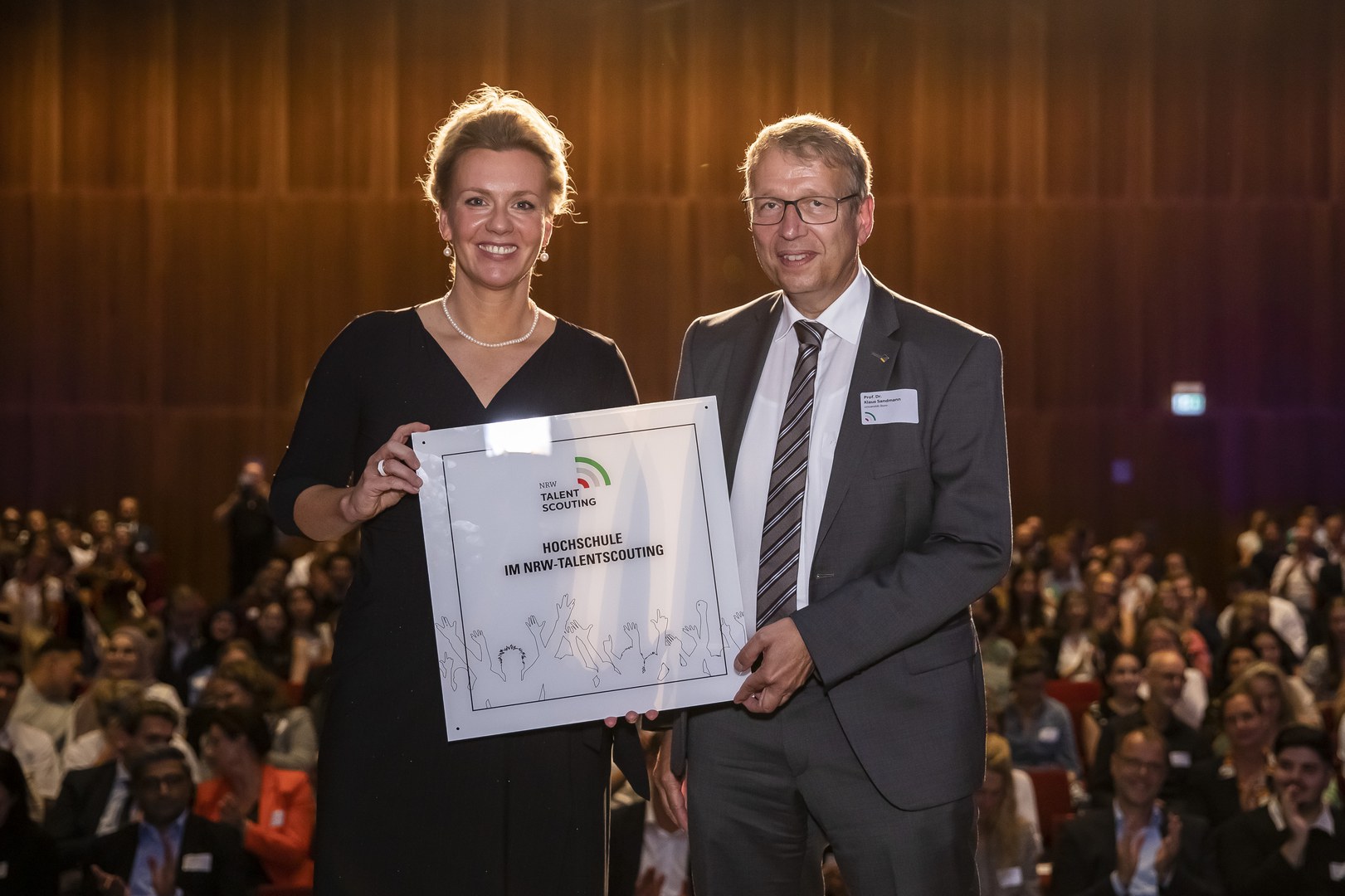 Ministerin Ina Brandes überreicht die offizielle Plakette an den Prorektor für Studium, Lehre und Hochschulentwicklung Prof. Dr. Klaus Sandmann.