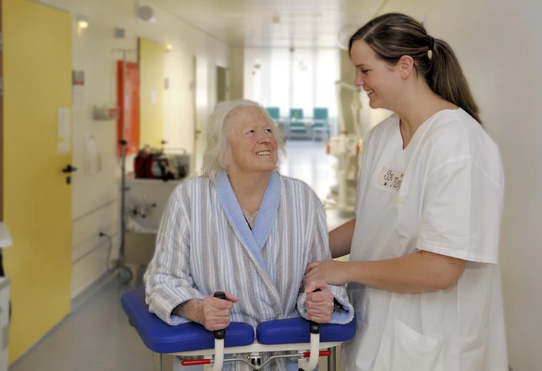 Eine Pflegeschülerin hilft einer Patientin