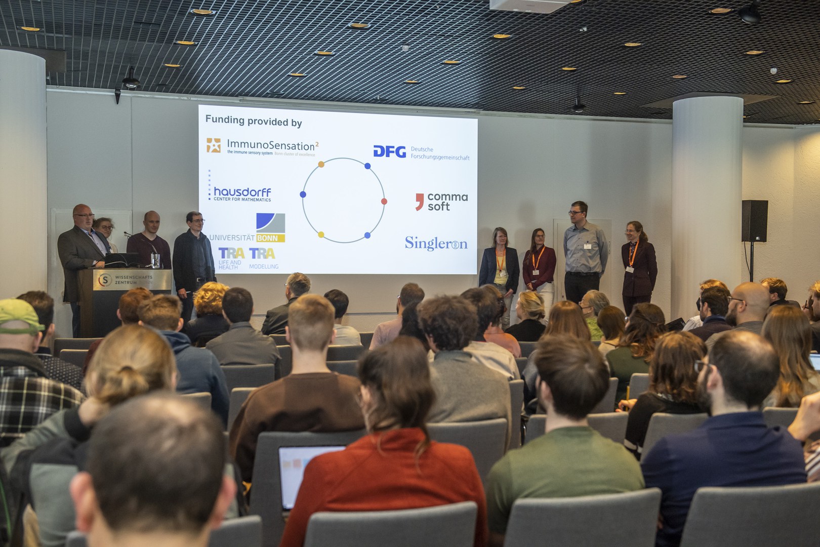 The organizing team welcomed the participants: from left to right Prof. Dr. Jan Hasenauer, Jun-Prof. Dr. Alena Khmelinskaia, Prof. Dr. Alexander Effland, Prof. Dr. Kevin Thurley, Dr. Meike Brömer (TRA "Life and Health"), Dr. Catherine Drescher (ImmunoSensation2), Dr. Daniel Minge (TRA "Modelling") and Dr. Sonja Dames (Hausdorff Center for Mathematics, HCM).