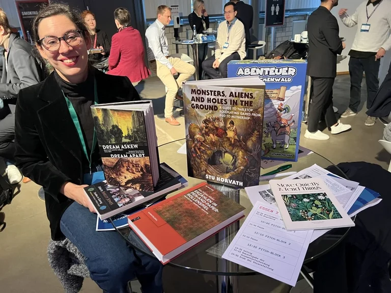 Kathrin Fischer with a selection of literature about tabletop roleplaying games